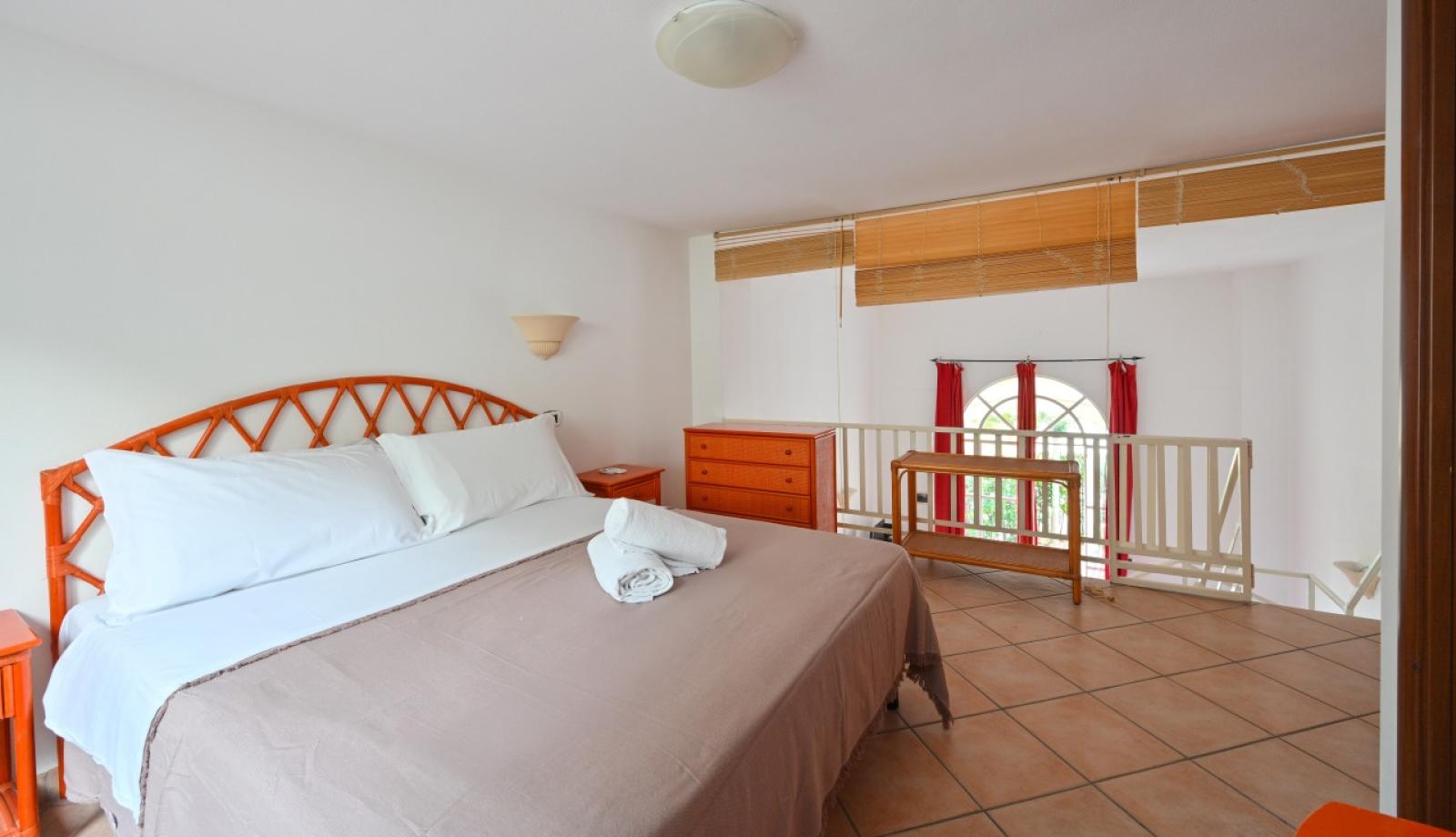 Camera da letto luminosa con letto matrimoniale e arredamento in legno.