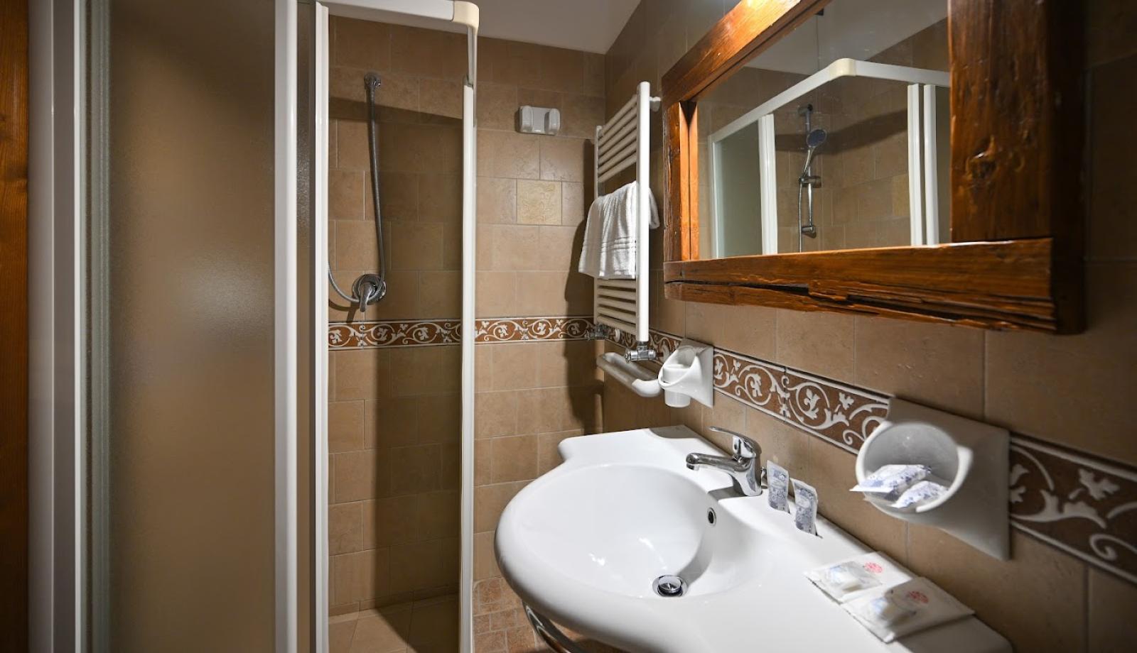 Bagno con doccia, lavabo, specchio in legno e decorazioni in ceramica.