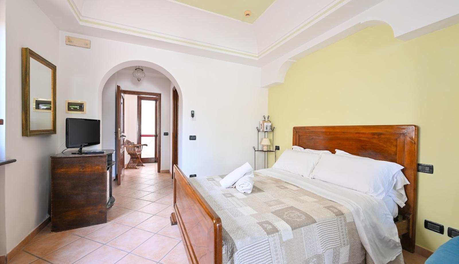 Camera accogliente con letto matrimoniale, TV e arredi in legno.