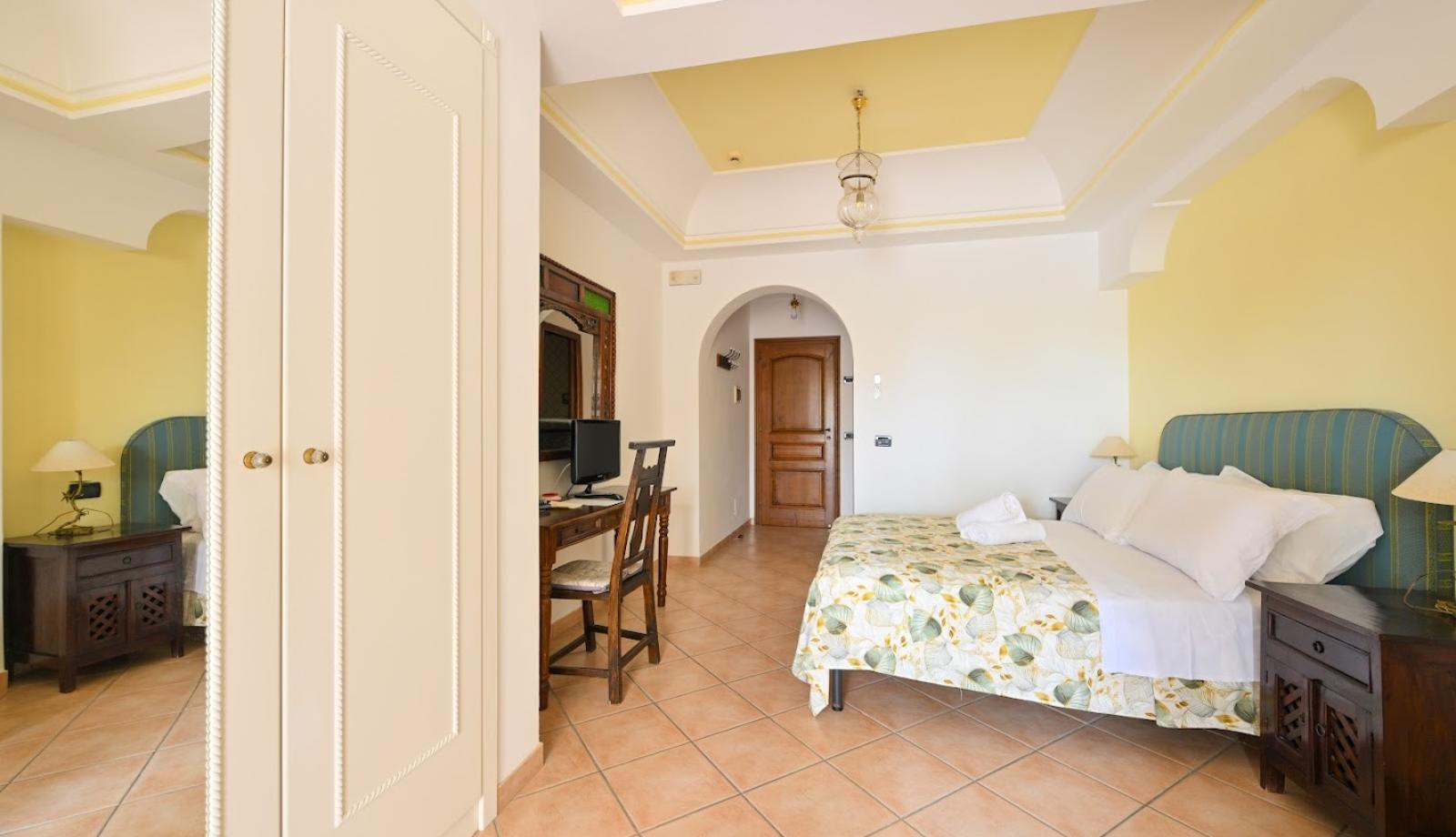 Camera accogliente con letto matrimoniale, armadio e scrivania, decorata in toni caldi.