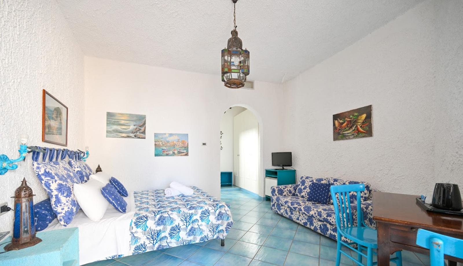 Camera luminosa con arredi blu, letto matrimoniale e decorazioni marine.