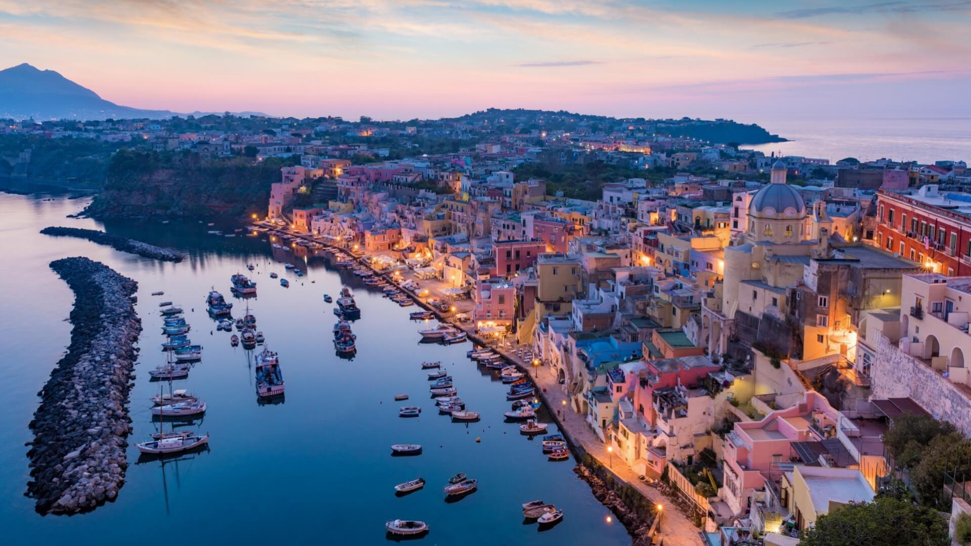 Vista serale di un pittoresco porto italiano con case colorate e barche.