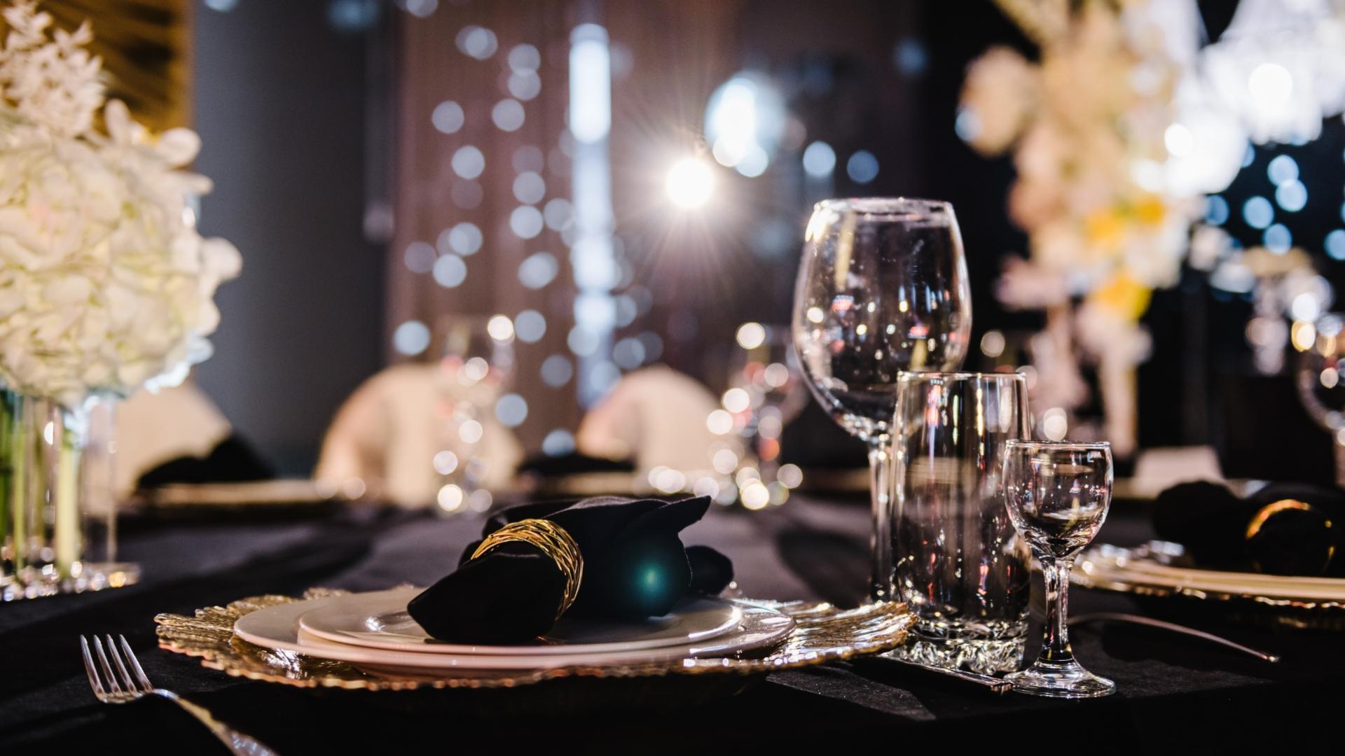 Tavola elegante con bicchieri di cristallo e tovagliolo nero su piatto decorato.