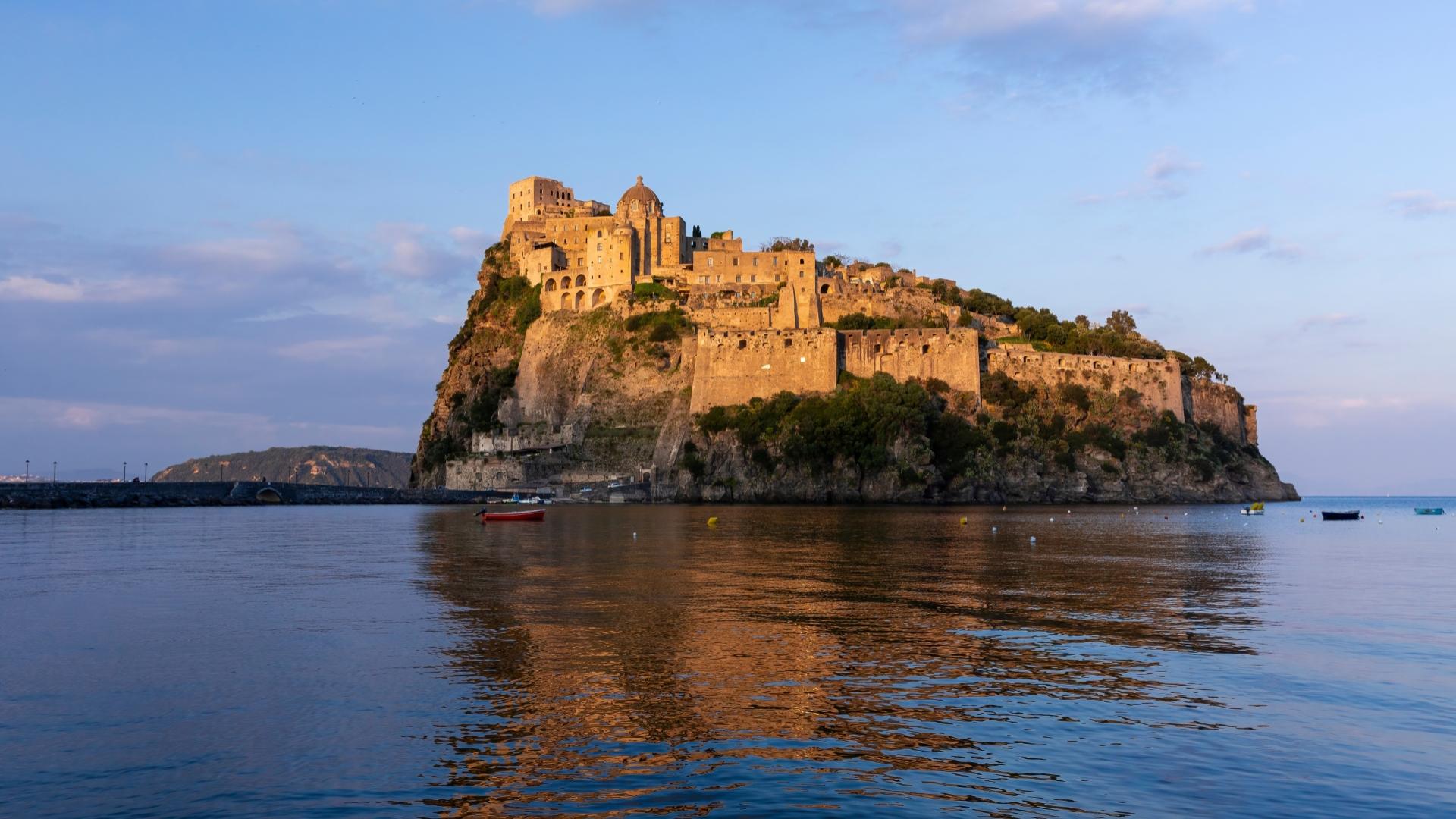 Castello Aragonese di Ischia al tramonto, riflesso nelle acque del mare.