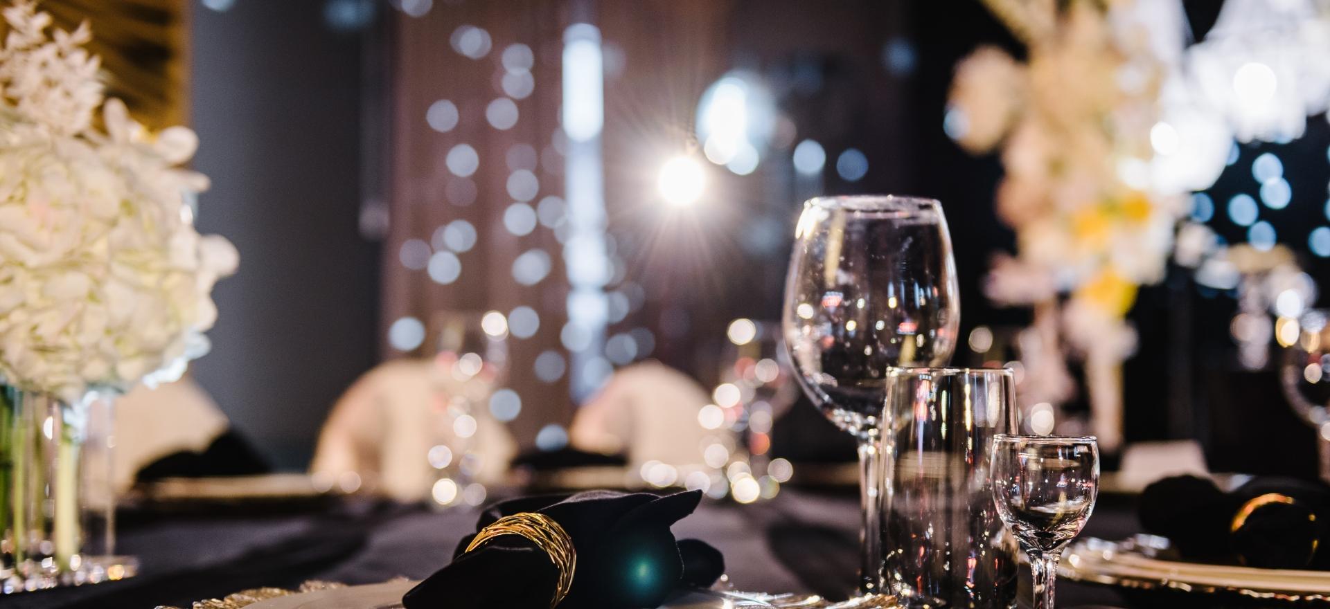 Tavola elegante con bicchieri di cristallo e tovagliolo nero su piatto decorato.
