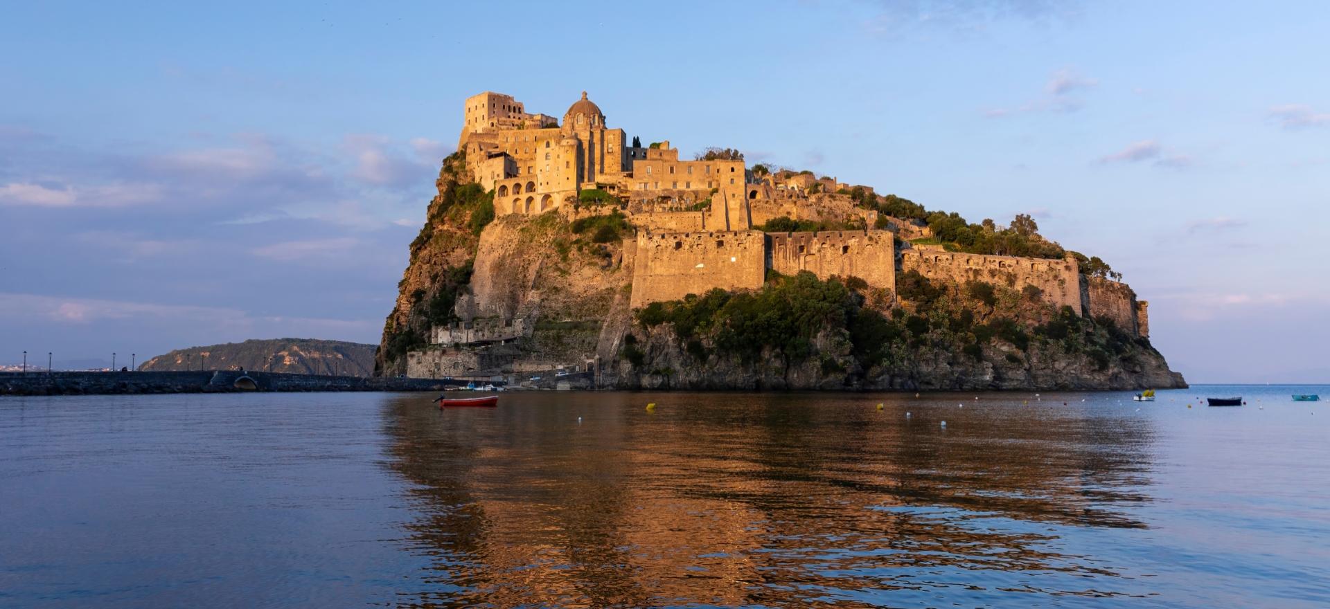 Castello Aragonese di Ischia al tramonto, riflesso nelle acque del mare.