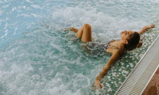Donna rilassata in piscina con idromassaggio, godendo il momento di tranquillità.