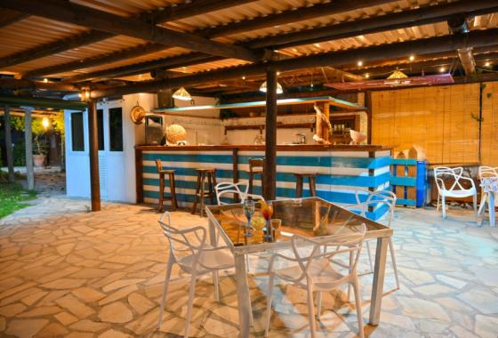 Bar all'aperto con tavoli, sedie bianche e illuminazione calda.