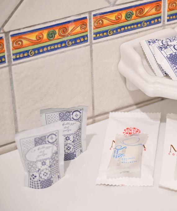 Articoli da bagno su un ripiano, con piastrelle colorate sullo sfondo.