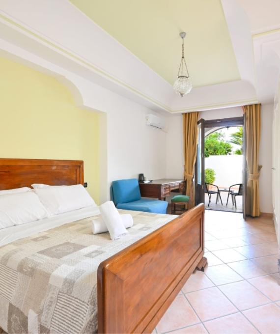 Camera accogliente con letto matrimoniale, scrivania e terrazza con vista giardino.
