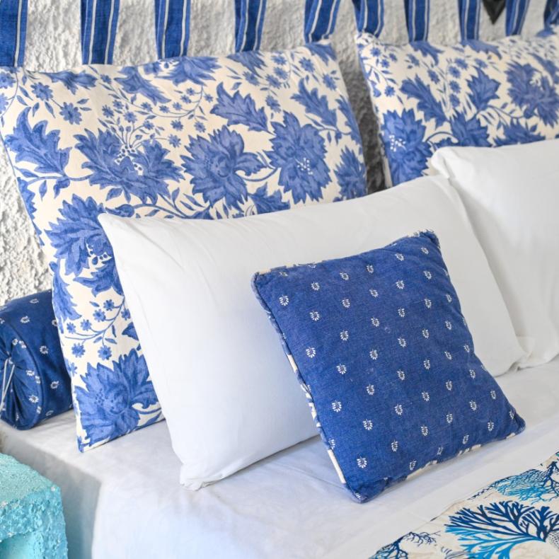 Letto con cuscini blu e bianchi in una stanza dallo stile marino.