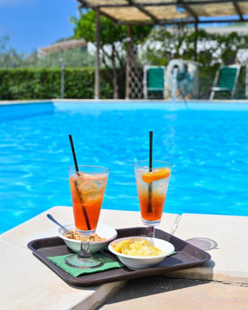 Due cocktail e snack su un vassoio accanto a una piscina.