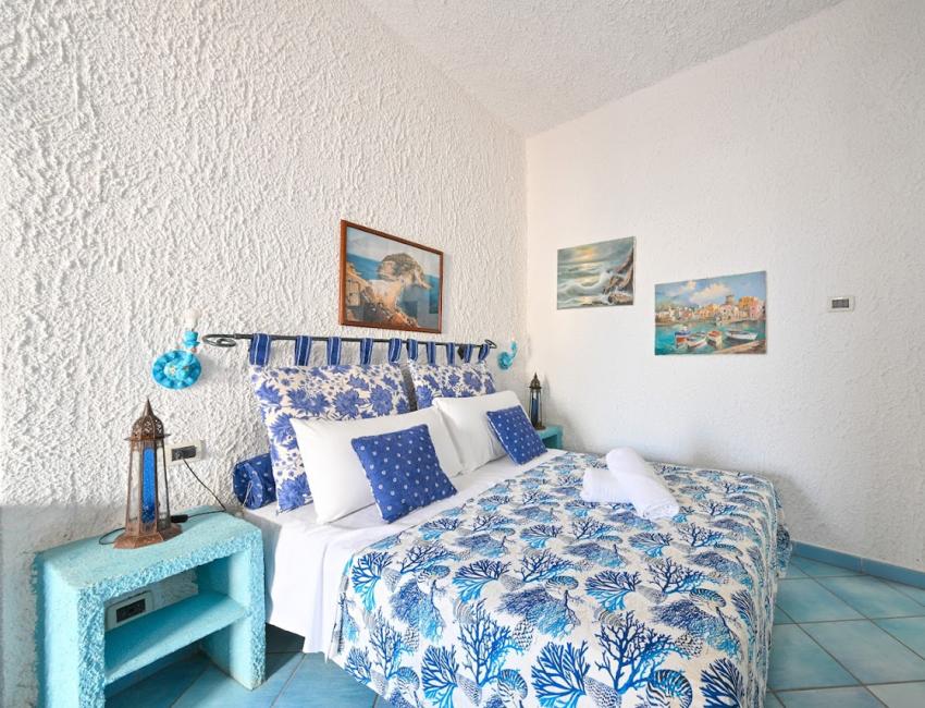 Camera luminosa con letto matrimoniale, decorazioni floreali e finestre ampie.