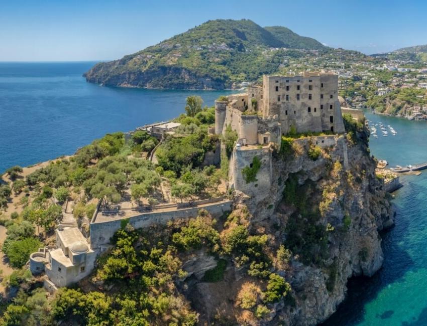 Castello su scogliera con vista sul mare e città costiera.