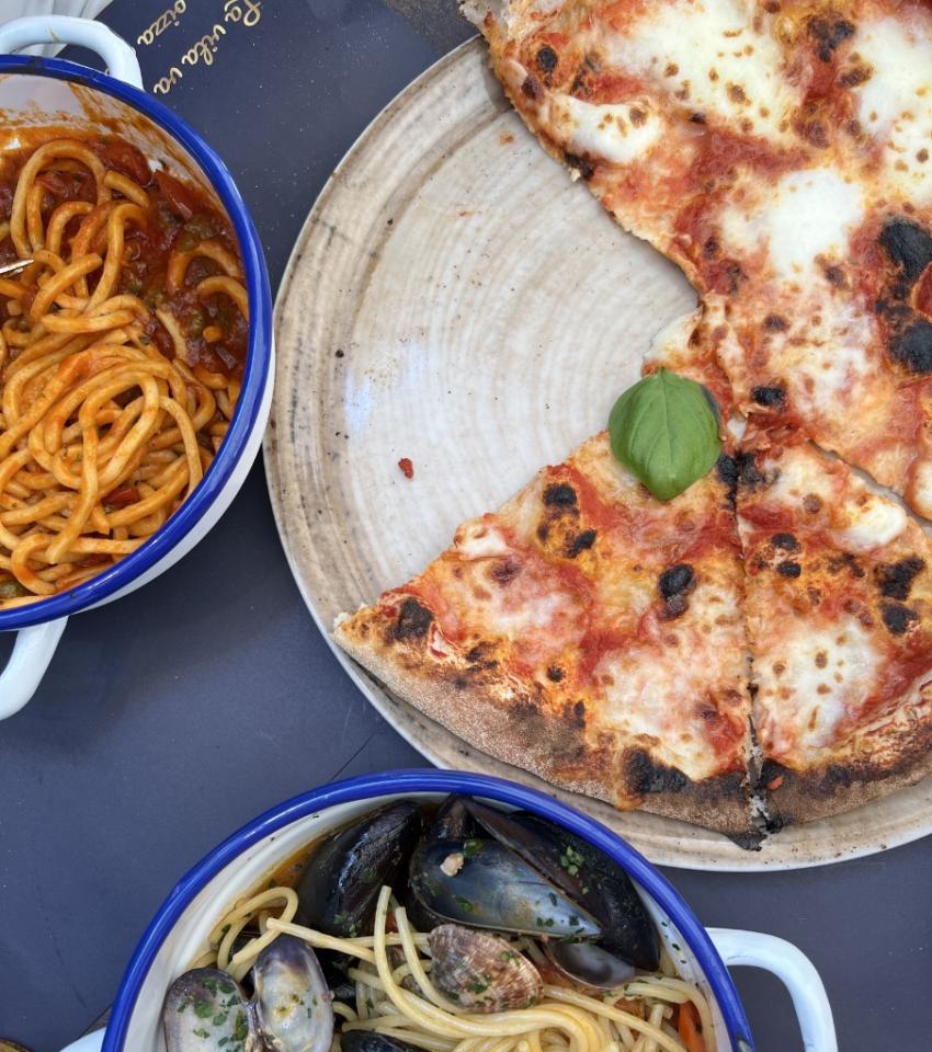 Pizza margherita, spaghetti ai frutti di mare e pasta al sugo in tavola.